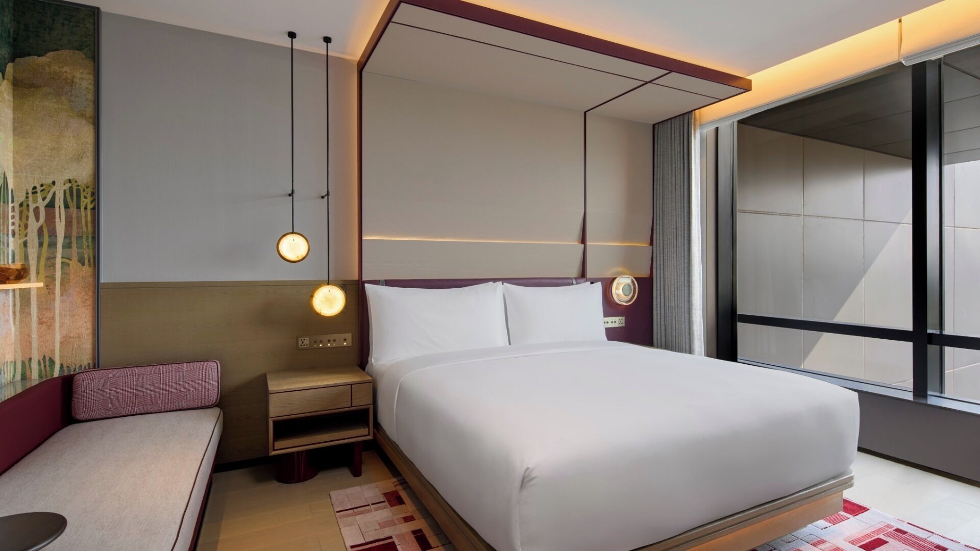 A modern hotel room with a large bed, bedside tables, a seating area, and a large window offering a view.