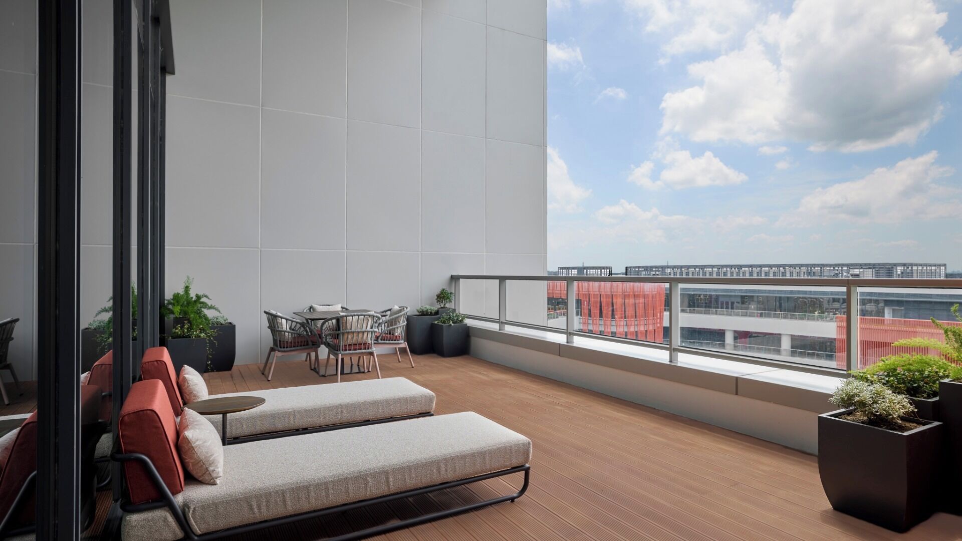 Un balcon moderne avec un canapé, des fauteuils et des plantes en pot.
