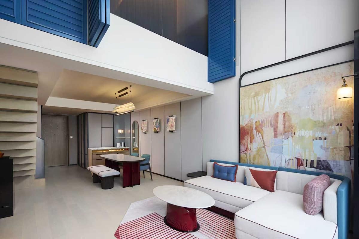 Un intérieur moderne comprenant un coin repas, un canapé et un grand tableau abstrait.