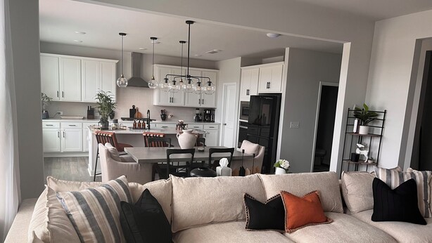 A modern living room with a beige sectional sofa, a dining area, and a kitchen with white cabinets and pendant lighting. - Spacious 7bedroom house in McDonough with Pool, WiFi, fitness room, and theater (McDonough)