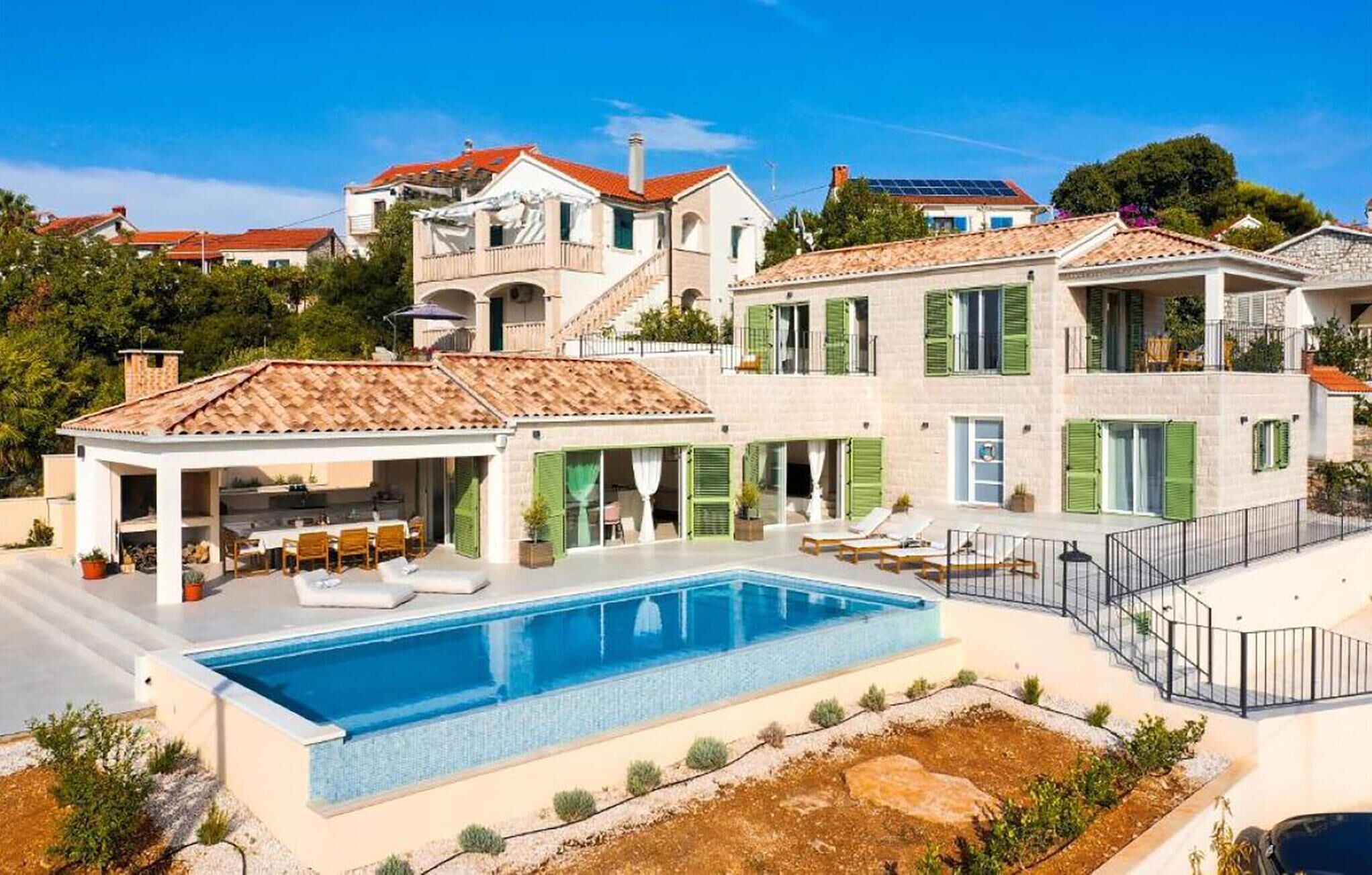 A residential property with a swimming pool, outdoor seating area, and multiple balconies.
