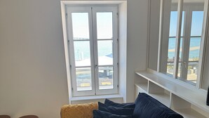 Ein modernes Wohnzimmer mit einem dunkelblauen Sofa, einem Holztisch und Meerblick durch große Fenster.