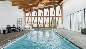 Una piscina con techo de madera y amplios ventanales.