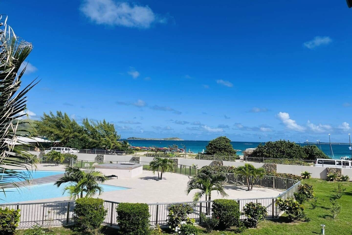 Un resort con piscina, palme e vista sull'oceano.