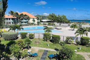 Um resort com piscina, palmeiras e vista para o oceano.