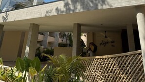 Un edificio moderno con múltiples ventanales arqueados y un área exterior cubierta con plantas.