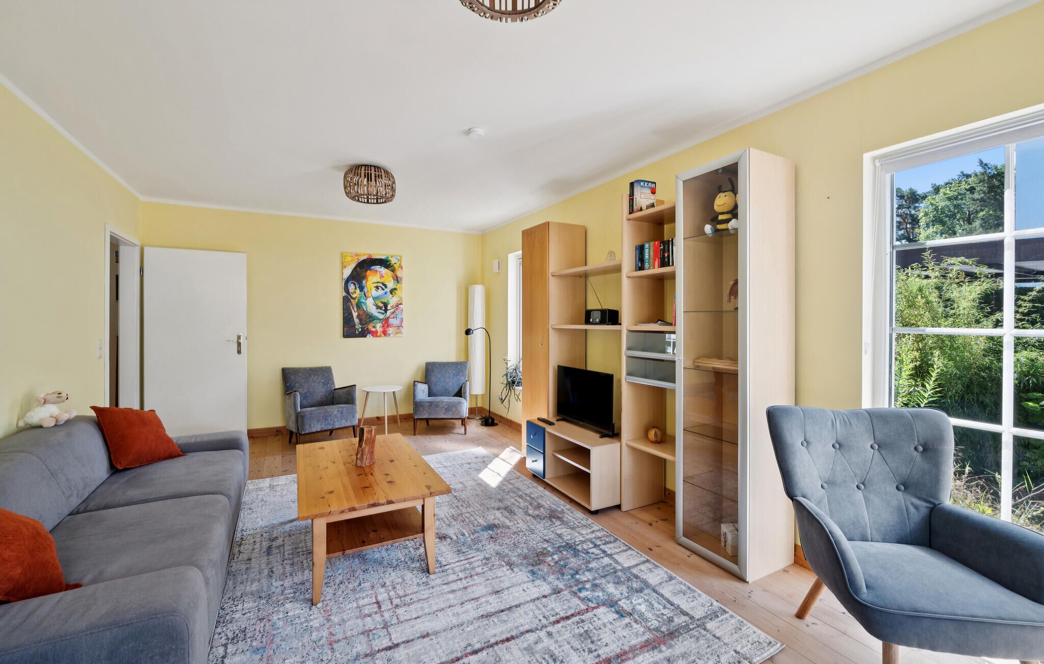 Een moderne woonkamer met een bank, fauteuils, een salontafel en een boekenkast.