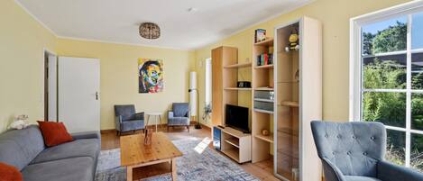 Een moderne woonkamer met een bank, fauteuils, een salontafel en een boekenkast.
