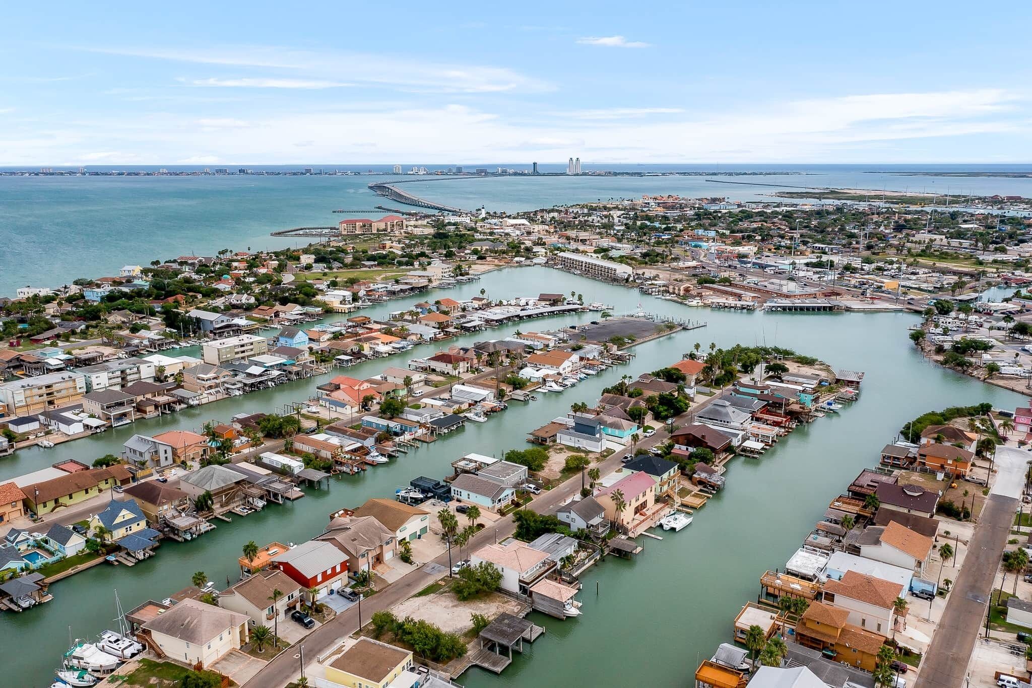 An aerial view of a coastal town with numerous waterfront properties and a marina.