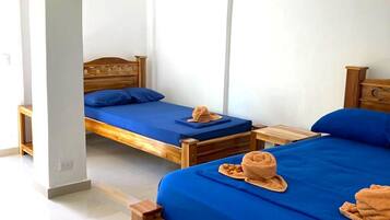 Una habitación con dos camas de madera, cada una con ropa de cama y toallas azules.