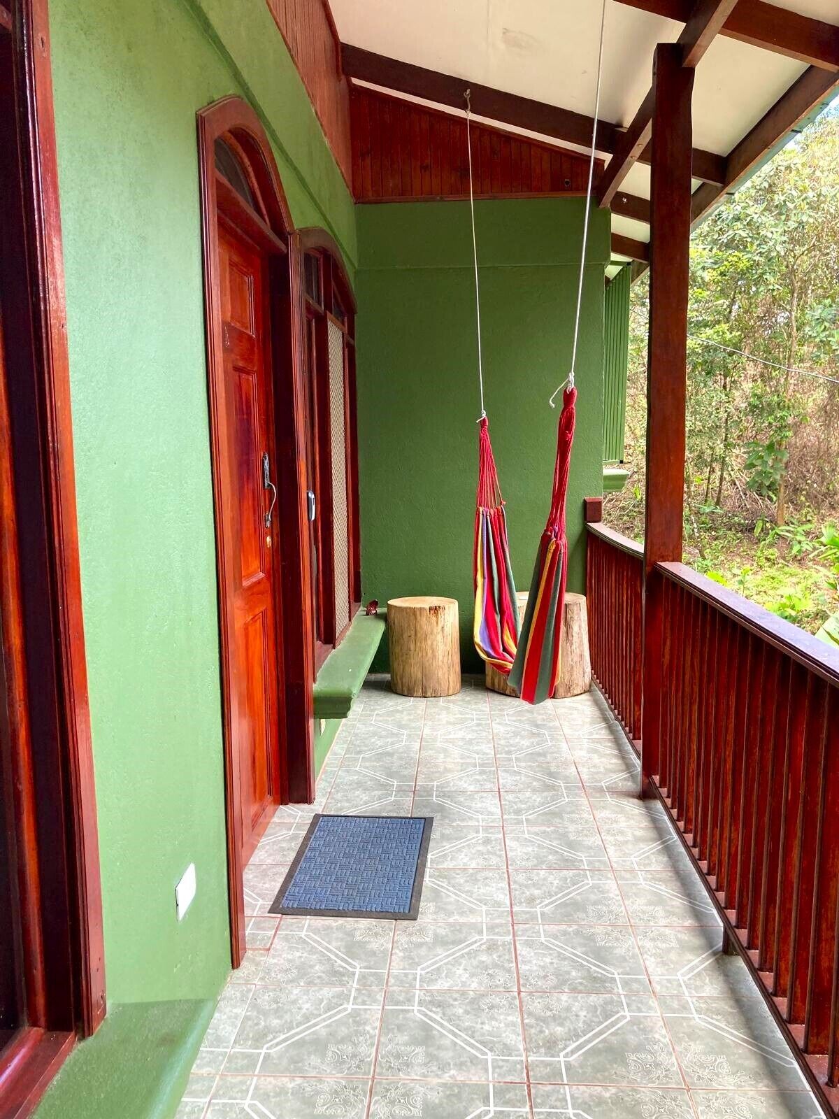 Une véranda couverte avec un mur végétal, des portes en bois et un sol carrelé.