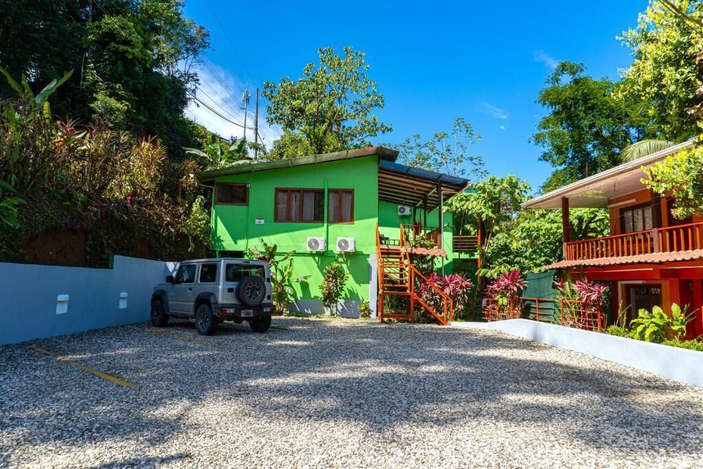 Un bâtiment vert avec une allée en gravier, une échelle et un bâtiment rouge en arrière-plan.
