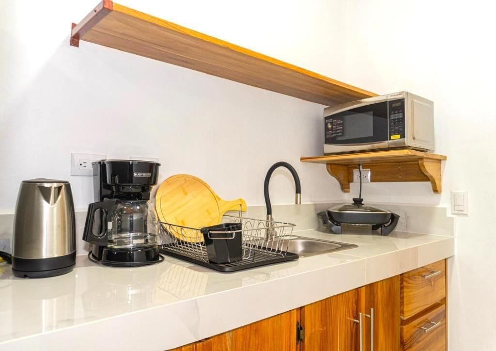 Une cuisine équipée d’un four à micro-ondes, d’une machine à café, d’une bouilloire et d’un égouttoir à vaisselle.