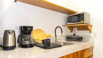 Une cuisine équipée d’un four à micro-ondes, d’une machine à café, d’une bouilloire et d’un égouttoir à vaisselle.