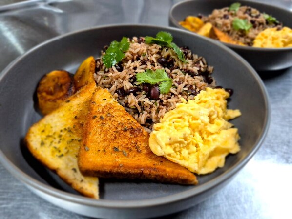 A plate with rice, black beans, scrambled eggs, and toasted bread.