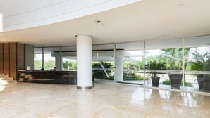 A spacious lobby with a reception desk, large windows, and a modern architectural design. - First line beach in Cartagena edif.morros 3 (Cartagena)
