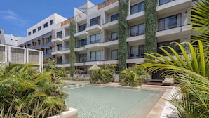 Et moderne hotel med swimmingpool, omgivet af frodigt grønt og palmer.