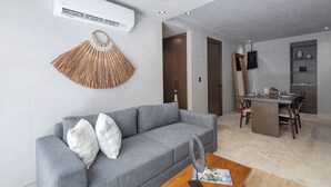 En moderne stue med en grå sofa, en ventilator og et spiseområde med bord og stole.