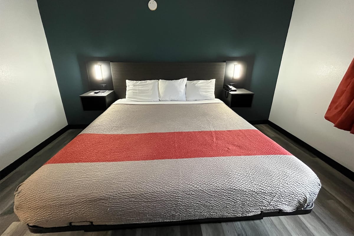 Ein Hotelzimmer mit einem Bett, zwei Nachttischen und einem Kopfteil.