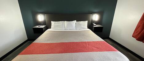 Una habitación de hotel con una cama, dos mesitas de noche y un cabecero.