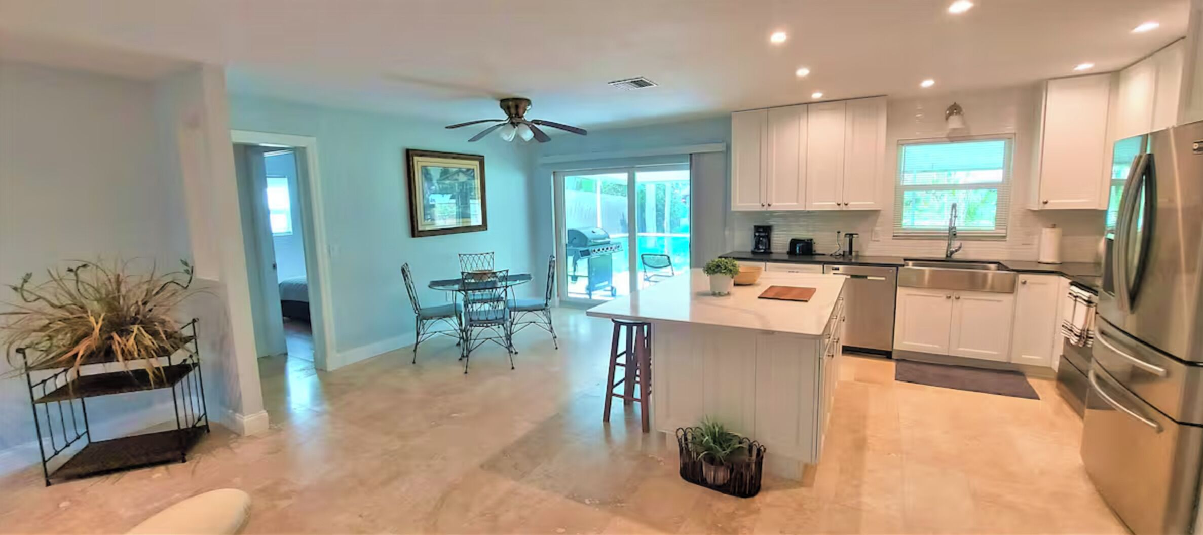 Una cocina moderna con armarios blancos, electrodomésticos de acero inoxidable y una isla central.