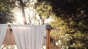 A wooden deck with potted plants, a white canopy, and a red chair.