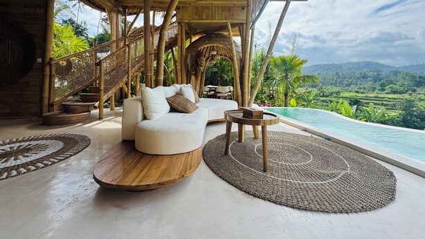 Una habitación lujosa con un sofá blanco, una mesa de centro de madera y vista a una piscina.