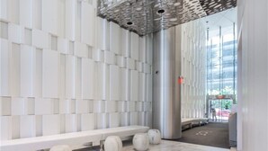 A modern interior with a white bench, spherical stools, and a patterned ceiling. - Modern Waterfront 3BR Escape with Free Parking (Toronto)