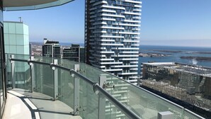 A high-rise building with a modern design, featuring a glass balcony railing and a view of the city and coastline. - Modern Waterfront 3BR Escape with Free Parking (Toronto)