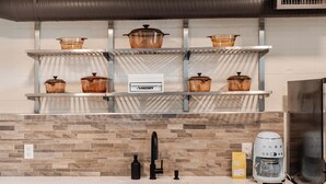 A kitchen with a marble countertop, a stainless steel sink, a coffee maker, and glass storage jars labeled "HUSKY" on shelves above. - East End Loft (Calgary)