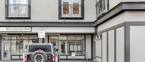 A building with a sign reading "Blooms on 9th" and a parked SUV.