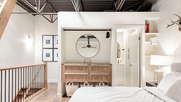 A bedroom with a bed, wooden dresser, and a ceiling fan. - East End Loft (Calgary)
