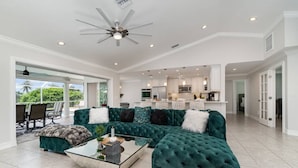 A spacious living room with a large sectional sofa, a glass coffee table, and a ceiling fan. - La Dolce Vita: Your Waterfront Jackpot (North Fort Myers)