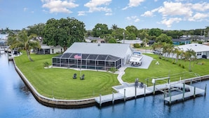 A waterfront property with a large covered area, a dock, and a boat. - La Dolce Vita: Your Waterfront Jackpot (North Fort Myers)