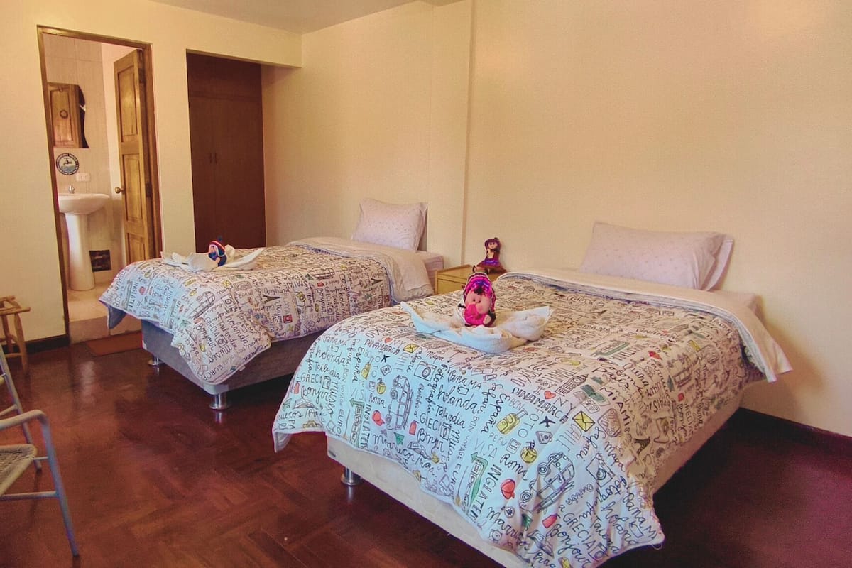 A room with two beds, a small table, and a chair.