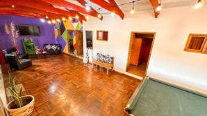Una stanza con pavimento in parquet a spina di pesce, un divano, una panca e una chitarra.