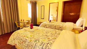 Una camera d'albergo con due letti, un tavolino e una sedia.