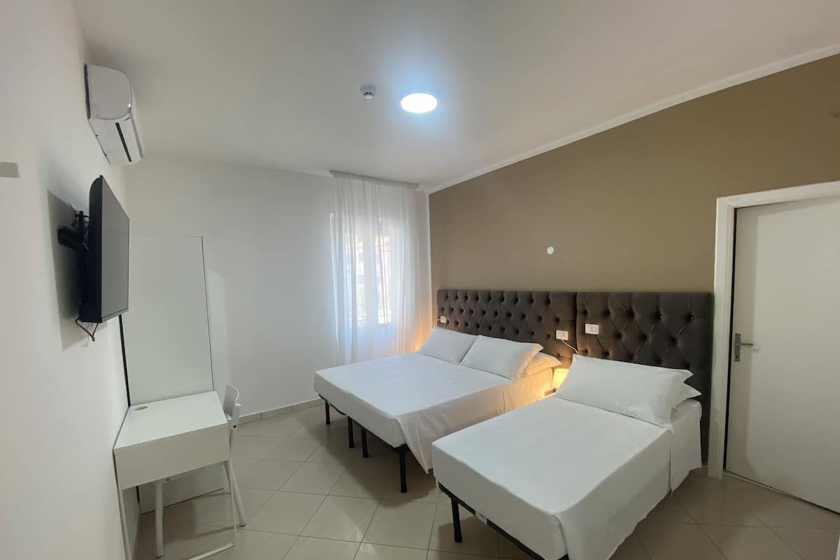 Una habitación de hotel con dos camas individuales, un escritorio, un televisor y una puerta.