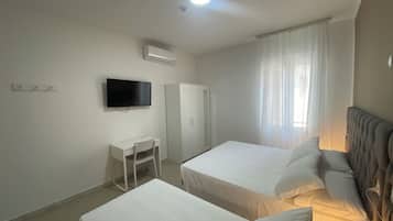 Habitación de hotel con dos camas, un escritorio, un televisor y aire acondicionado.