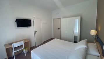 Ein Hotelzimmer mit Bett, Schreibtisch, Stuhl, an der Wand befestigtem Fernseher und Kleiderschrank.