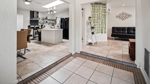 A modern kitchen with a central island, a dining area with a table and chairs, and a living room with a black sofa. - 3-bedroom house in beautiful Tucson with WiFi, AC (Tucson)