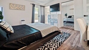 A modern bedroom with a bed, a TV, a wardrobe, and a chair. - 3-bedroom house in beautiful Tucson with WiFi, AC (Tucson)