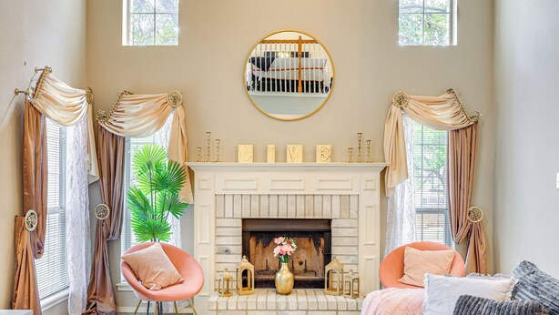 A living room with a fireplace, two chairs, a sofa, and curtains.