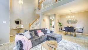 A spacious living area with a sectional sofa, a dining table with chairs, and a staircase leading to an upper level.