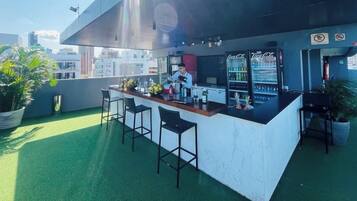 Un bar en la azotea con mostrador, asientos y un refrigerador de Coca-Cola.