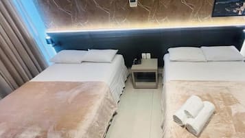 Een hotelkamer met twee bedden, een nachtkastje, een wandairconditioner en een klein fotolijstje.