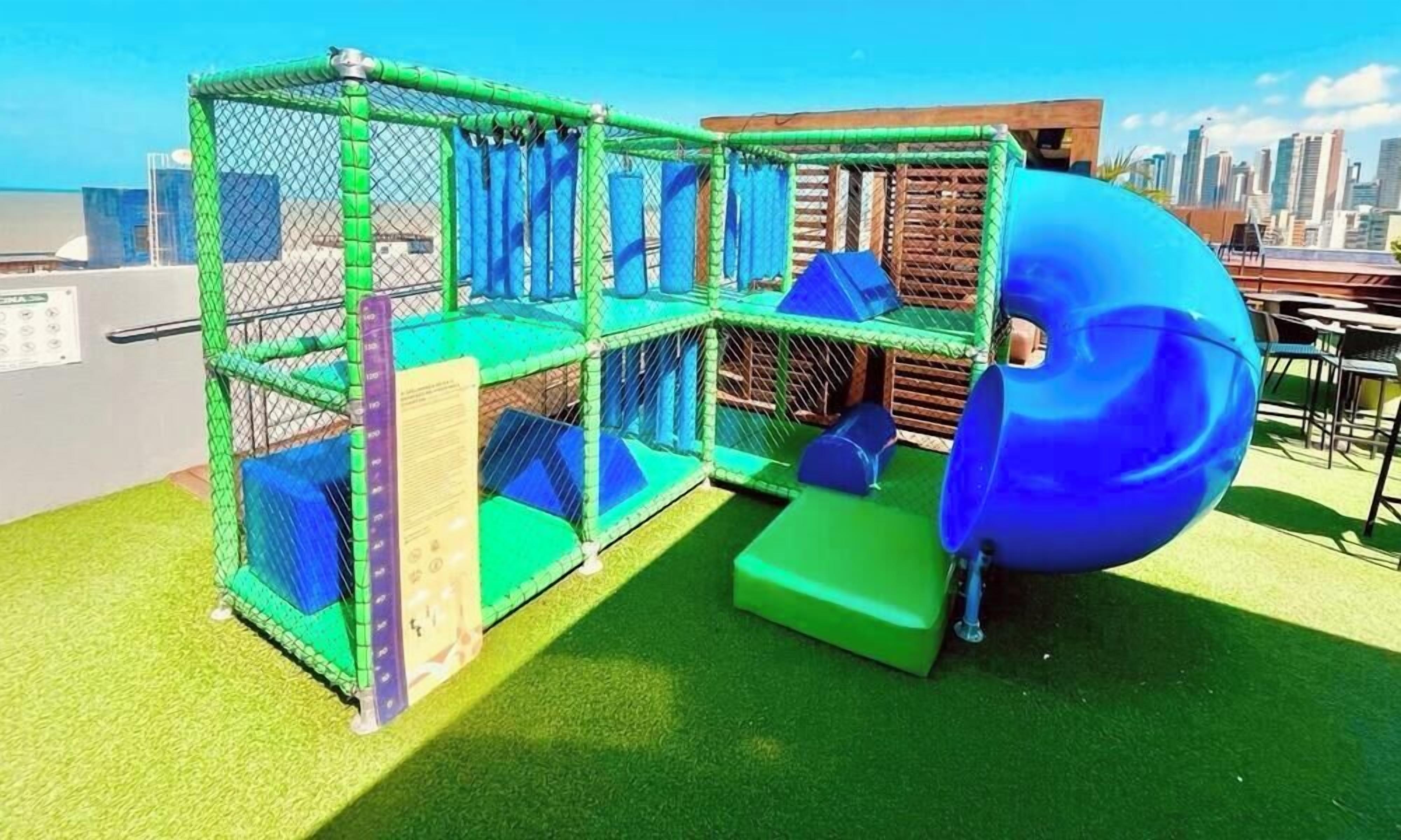 A playground with a slide and netted play area.