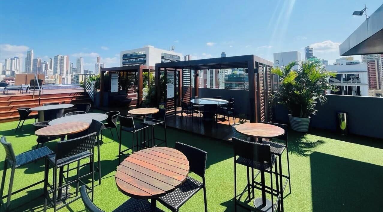 Un espacio al aire libre con mesas y sillas, con vistas al horizonte de la ciudad.