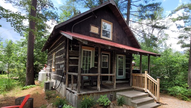 Eine rustikale Holzhütte mit Veranda, umgeben von Bäumen.