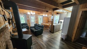 Ein gemütliches Blockhaus mit Kamin, Ledersofa, Esstisch aus Holz und Küchenzeile.
